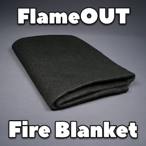 May include: A black fire blanket folded in half, with the text "FlameOUT Fire Blanket" printed below it.