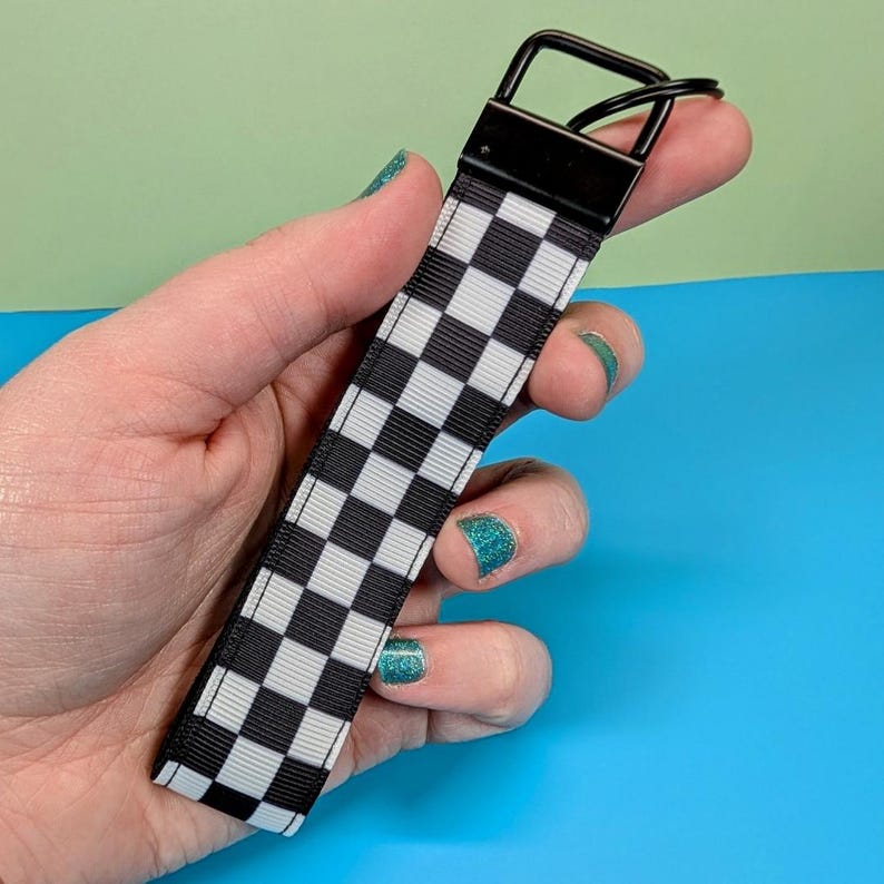 May include: Black and white checkered keychain with a black metal key ring.