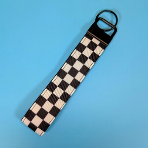 May include: Black and white checkered keychain with a black metal key ring.