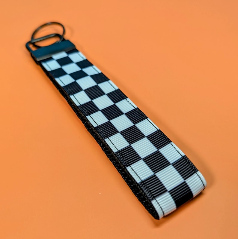 May include: Black and white checkered keychain with a black metal ring.