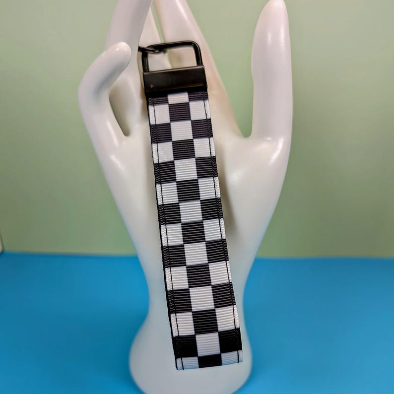 May include: Black and white checkered keychain with a black metal ring.