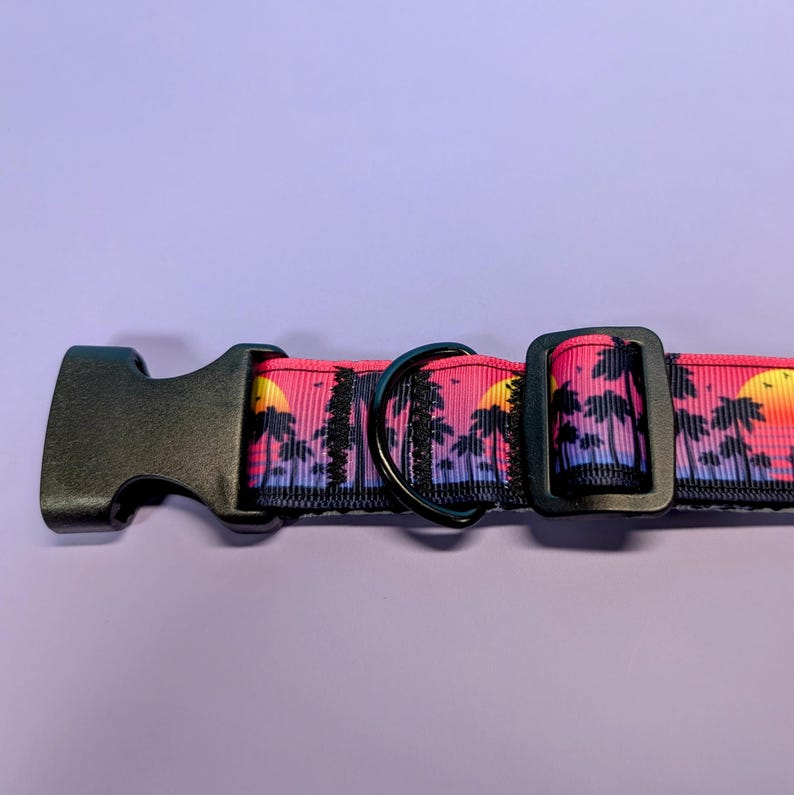 May include: Black dog collar with a pink and purple sunset and palm tree print.
