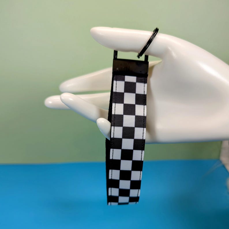 May include: Black and white checkered keychain with a black metal ring.