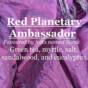 May include: A purple and green textured background with the text "Red Planetary Ambassador Favoured by folks named Sarek Green tea, myrtle, salt, sandalwood, and eucalyptus."