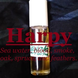 May include: A clear glass bottle with a white cap and a label that reads "Soulmate" and "Harpy". The label also lists the scent notes: "Sea water, blood, smoke, oak, spruce, and feathers."
