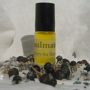 May include: A small glass bottle with a black cap and a yellow liquid inside. The bottle has a label that reads "Soulmate Berry-ka Scent".