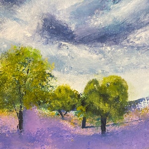 May include: An original landscape painting featuring a field of lavender flowers under a cloudy sky. The artwork depicts several green trees in the foreground, with rolling hills in the background. The color palette includes shades of purple, green, and blue.