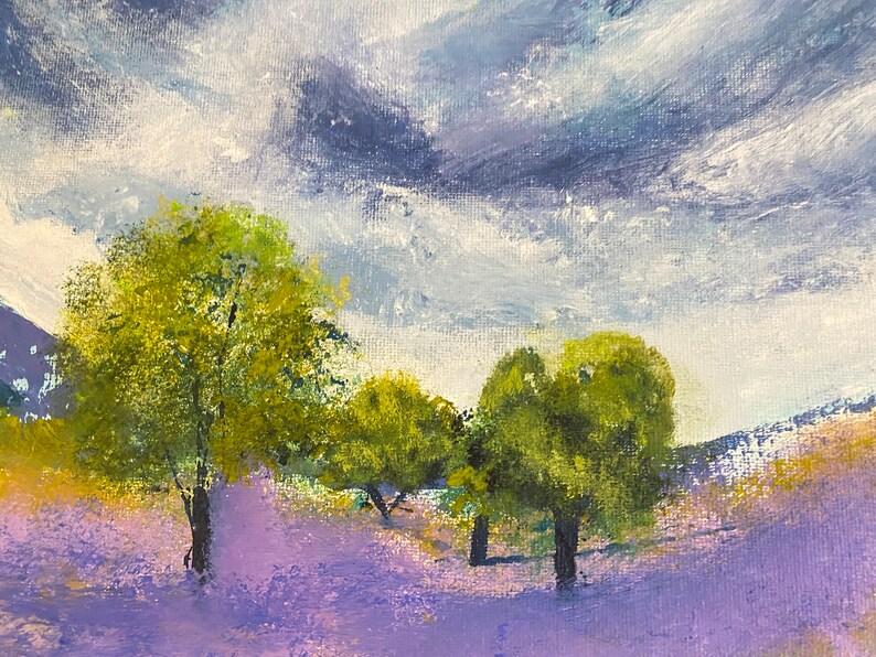 May include: An original landscape painting featuring a field of lavender flowers under a cloudy sky. The artwork depicts several green trees in the foreground, with rolling hills in the background. The color palette includes shades of purple, green, and blue.