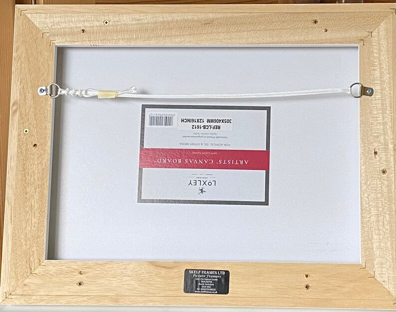 May include: Back of a framed canvas board, with a light wood frame. The canvas is labeled "ARTISTS' CANVAS BOARD" and measures 12 x 16 inches. A white cord is strung across the back for hanging.