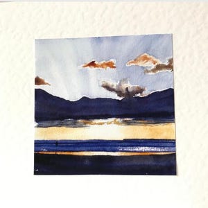 K&ouml;nnte beinhalten: Aquarellmalerei einer Landschaft mit Sonnenuntergang &uuml;ber dem Wasser. Der Himmel ist hellblau mit orangefarbenen und grauen Wolken. Dunkelblaue Berge befinden sich im Hintergrund, und das Wasser reflektiert die Farben des Sonnenuntergangs.
