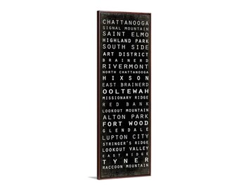 May include: Black and white typography print with the names of neighborhoods in Chattanooga, Tennessee. The print is framed in a dark brown wood frame.