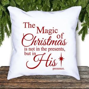 May include: White throw pillow with red text that reads "The Magic of Christmas is not in the presents, but in His presence."
