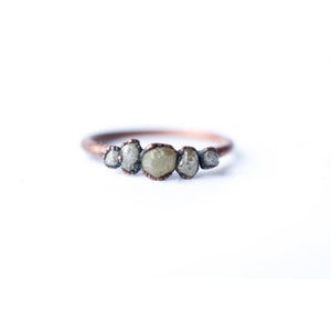 May include: A copper ring with five rough, grey diamonds set in a row.