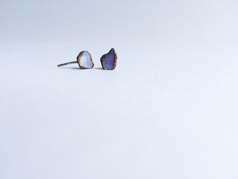 Pu&ograve; includere: Un paio di orecchini a lobo in argento con pietre di opale iridescenti. Le pietre hanno una forma irregolare e un aspetto naturale e grezzo.