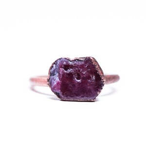 May include: A copper ring with a raw, purple ruby gemstone set in the centre.