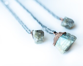 Puede incluir: Tres cadenas de plata con colgantes de piedra de labradorita. El colgante más grande está envuelto en alambre de cobre.