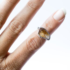 May include: A silver ring with a clear and brown crystal stone set in a wire frame.