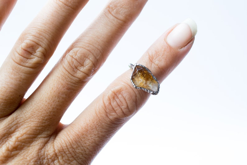 May include: A silver ring with a clear and brown crystal stone set in a wire frame.