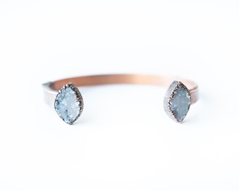 May include: A copper cuff bracelet with two clear quartz crystal accents.