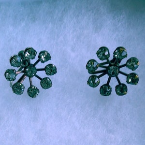 Może przedstawiać: Para srebrnych kolczyków z wzorem gwiazdy. Każdy kolczyk ma osiem przezroczystych cyrkonii osadzonych w wzorze gwiazdy.