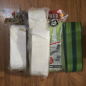 Può includere: Assortimento di cinghie e materiali di riparazione per mobili da esterno. Include rotoli di fettuccia bianca, fettuccia a righe verdi e bianche e fettuccia verde con strisce verde scuro. La confezione riporta "WEB 34 FEET" e "OURSELF...IT'S SO EASY (13 YDS.) x 5.7 cm."