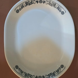 Puede incluir: Un plato ovalado blanco con un diseño floral negro alrededor del borde.