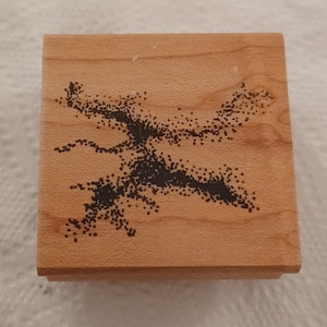 May include: A square wooden stamp with a black dotted design resembling a tree or abstract shape. The stamp is made of light-colored wood and has a simple, clean design. The stamp is likely used for crafts or art projects.