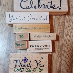 May include: A set of wooden rubber stamps with various phrases and designs, including "Celebrate!", "You're Invited", "Just want to say...", "To:", "A Gift For You", "From:", "Thank You", and "Thank You" with a butterfly and flowers.