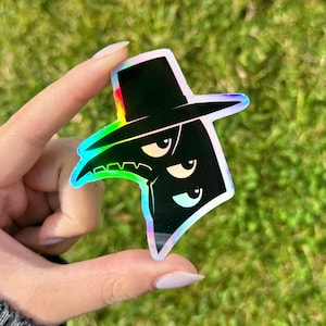 May include: A holographic sticker featuring a stylized black plague doctor with a hat and a beak-like mask. The sticker has a rainbow iridescent effect and a cartoonish design, with a green and yellow outline.