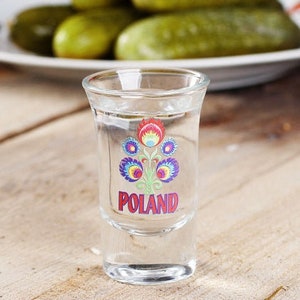 Pu&ograve; includere: Un bicchierino da shot in vetro trasparente con un motivo floreale colorato e la parola "POLAND" stampata sul davanti.