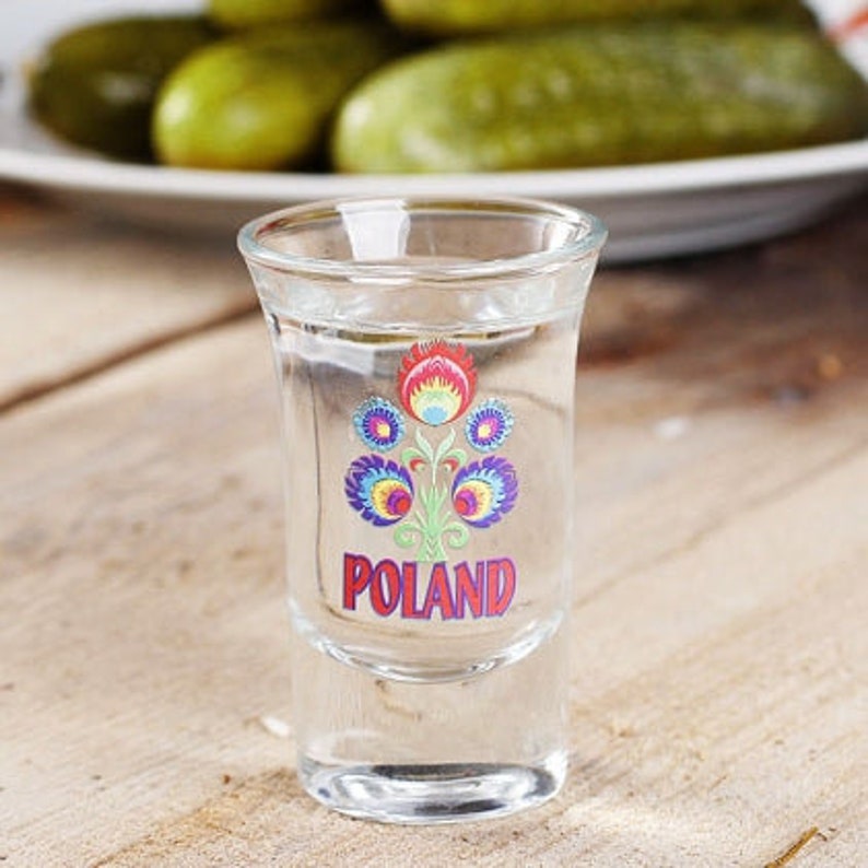 Pu&ograve; includere: Un bicchierino da shot in vetro trasparente con un motivo floreale colorato e la parola "POLAND" stampata sul davanti.