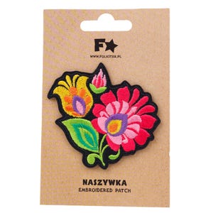 May include: Embroidered patch featuring a vibrant floral design with red, pink, yellow, and purple petals, and green leaves. The patch is on a brown card with the text "NASZYWKA EMBROIDERED PATCH" and the logo of a star and the text "WWW.FOLKSTAR.PL".