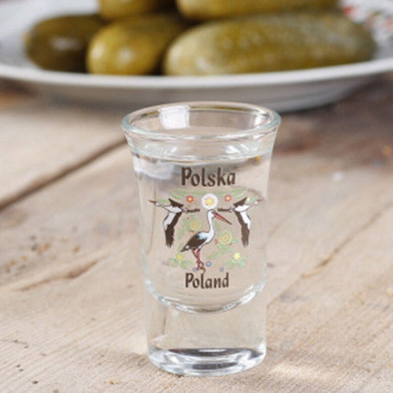 Pu&ograve; includere: Un bicchierino da shot in vetro trasparente con un disegno di due cicogne bianche e il testo "Polska Poland" su di esso.