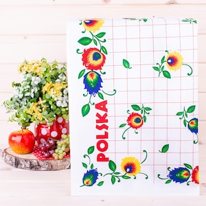 May include: White kitchen towel with a red, yellow, blue, and green floral pattern. The word "POLSKA" is written vertically on the towel in red letters.