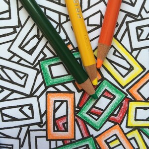 Puede incluir: Tres lápices de colores, verde, amarillo y naranja, están sobre una superficie blanca con un patrón geométrico en blanco y negro. Los lápices están etiquetados como "Prismacolor" y "Prismacolor 1300".