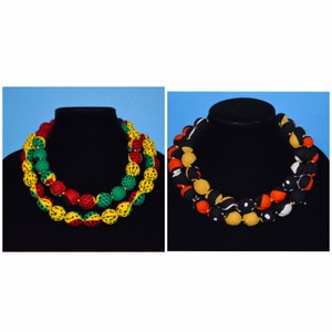 Puede incluir: Dos collares de tela con cuentas de patrones coloridos. El collar de la izquierda tiene cuentas rojas, amarillas y verdes. El collar de la derecha tiene cuentas negras, blancas, naranjas y amarillas.