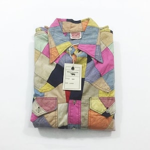 May include: A long-sleeve button-down shirt featuring a multi-colored patchwork design in shades of pink, yellow, orange, blue, and black. The shirt includes a pointed collar, two front chest pockets with button flaps, and a white paper tag.
