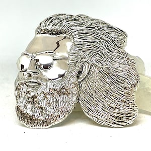 May include: A silver-toned metal sculpture of a man's face with a beard and sunglasses. The sculpture is detailed and realistic.
