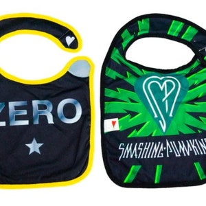 May include: Two black bibs with yellow trim. One bib has the word "ZERO" printed on it in silver lettering with a star below. The other bib has a green and black design with a heart and the words "Smashing Pumpkins" printed on it.