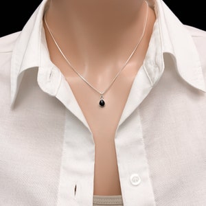 May include: A silver chain necklace with a small black teardrop pendant.