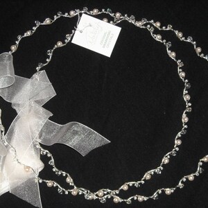 May include: A double strand silver headband with small white pearls and clear crystals. The headband is tied with a white satin ribbon.
