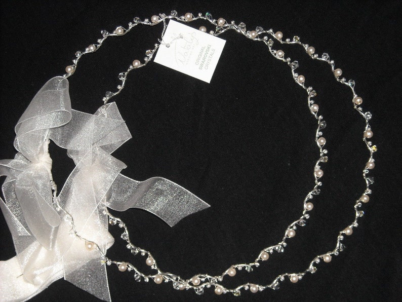 May include: A double strand silver headband with small white pearls and clear crystals. The headband is tied with a white satin ribbon.