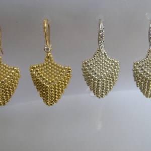 以下が含まれることがあります： 涙の形をしたぶら下がり式のイヤリングが4組。2組は金で、上部に透明な石が1つ付いており、2組は銀で、上部に透明な石が1つ付いています。