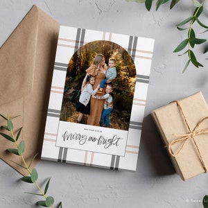 May include: A Christmas card with a plaid background and a photo of a family in a forest. The text "May your days be merry and bright" is written in cursive.