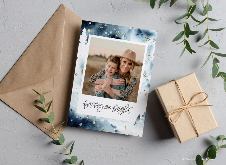 May include: A blue and white watercolor Christmas card with gold glitter accents. The card features a photo of a woman and child smiling and hugging. The text "merry and bright" is written in black calligraphy.