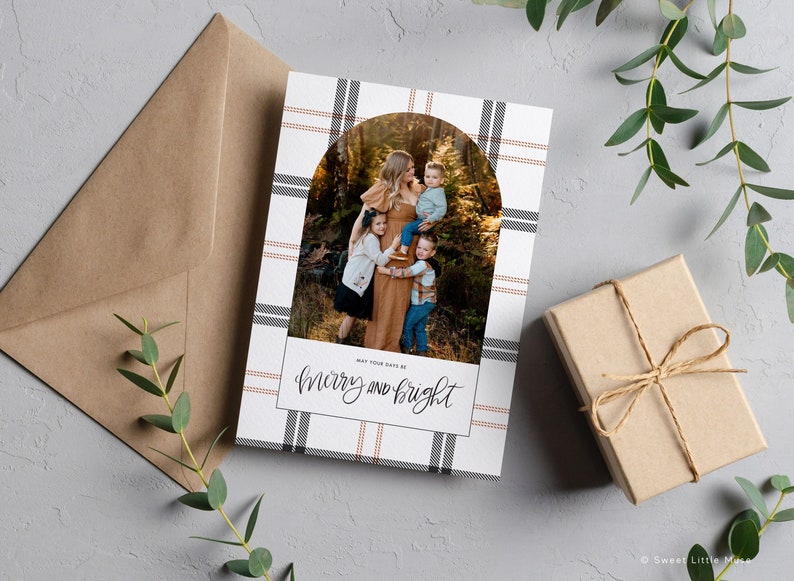 May include: A Christmas card with a plaid background and a photo of a family in a forest. The text "May your days be merry and bright" is written in cursive.