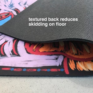 May include: A colorful, abstract design printed on a non-slip yoga mat. The back of the mat is black and textured to prevent slipping on the floor. "textured back reduces skidding on floor" is written on the mat.