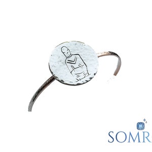 May include: A silver bracelet with a round charm featuring a hand-drawn image of a person. The charm has a hammered texture.