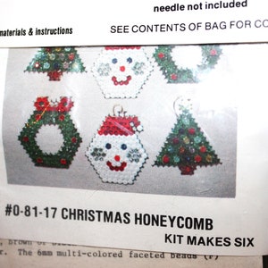 May include: A Christmas honeycomb kit with six designs, including a wreath, snowman, and Christmas tree. The kit features multi-colored faceted beads and the text "#0-81-17 CHRISTMAS HONEYCOMB KIT MAKES SIX".