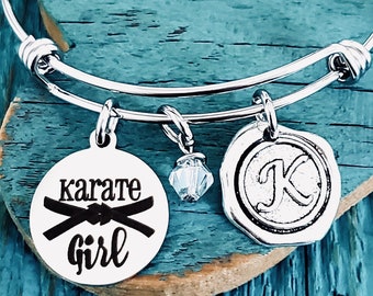 May include: Silver charm bracelet with a karate girl charm, a crystal charm, and a letter K charm.